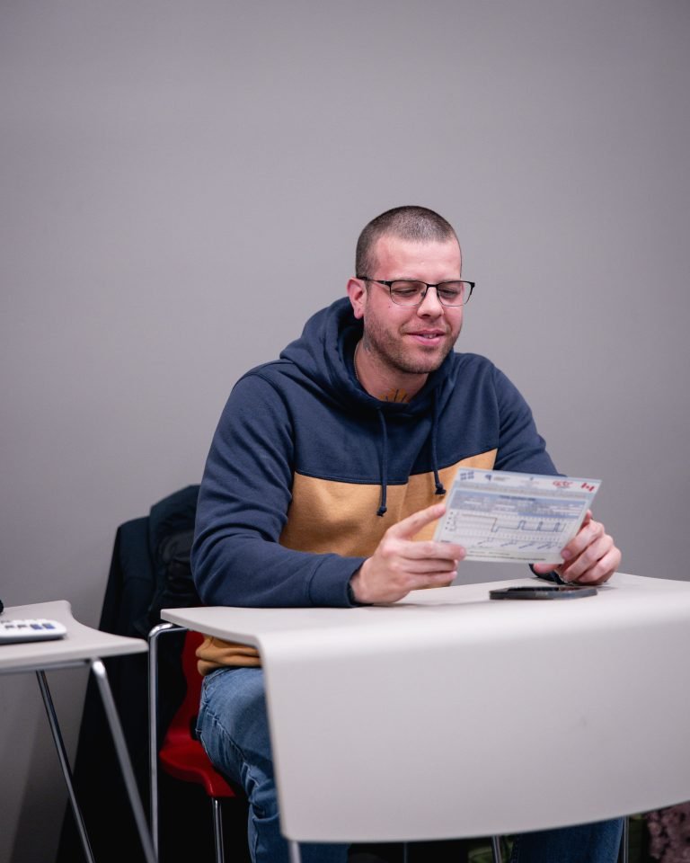 Étudiant lisant une fiche d'information avec le sourire.
